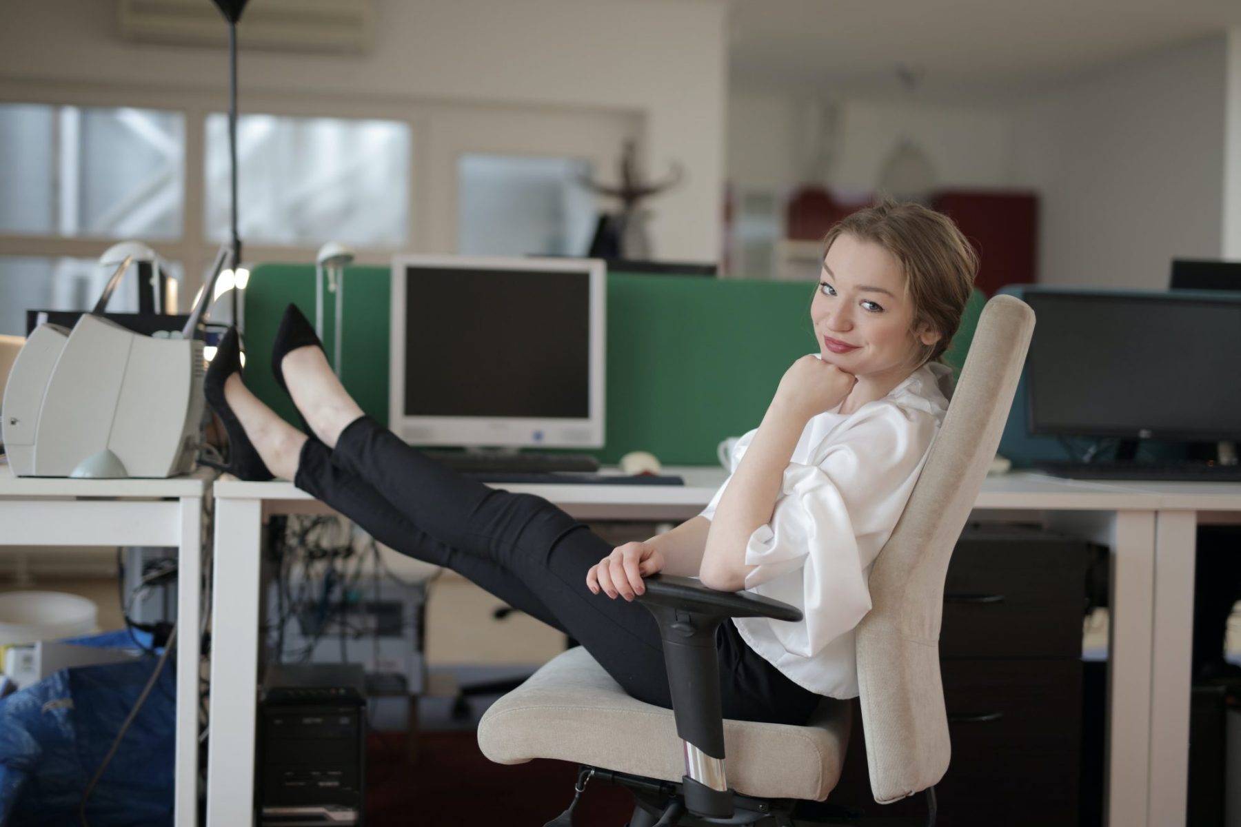 Successful woman with leg propped up on a desk after learning how to market yourself as a virtual assistant