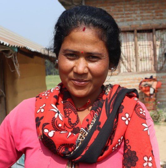 Woman with black hair and a red scarf smiling and learning about the microloan program
